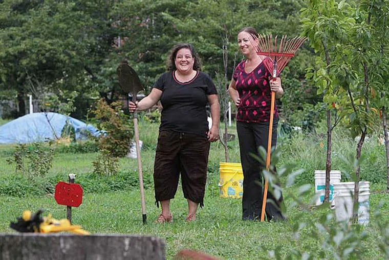 Volunteers Kate Riccardi (left) and Nancy Houston stand in the community garden outside Eastern State Penitentiary that was installed on land that had been used as a dog run. (Steven M. Falk/Staff)