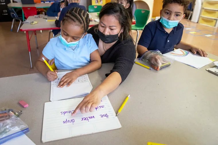 Paraprofessional Kim Son works at the Henry Davis Family School in Camden, New Jersey, Tuesday morning, April 5, 2022. She is working on writing skills with Shillan Reese, 6, while Jacian Jerez sits at right.