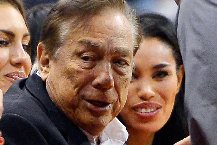 In this photo taken on Friday, Oct. 25, 2013, Los Angeles Clippers owner Donald Sterling, center, and V. Stiviano, right, watch the Clippers play the Sacramento Kings during the first half of an NBA basketball game, in Los Angeles. The NBA is investigating a report of an audio recording in which a man purported to be Sterling makes racist remarks while speaking to Stiviano.  NBA spokesman Mike Bass said in a statement Saturday, April 26, 2014, that the league is in the process of authenticating the validity of the recording posted on TMZ's website. Bass called the comments "disturbing and offensive."  (AP Photo/Mark J. Terrill)