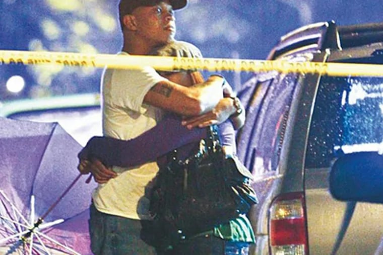 A couple&rsquo;s embrace punctuates the tragic scene Monday night as police investigate the double homicide on Sparks Street near 3rd in Olney. Two 21-year-old friends sitting on a porch were gunned down, cops said. (Joseph Kaczmarek/For the Daily News)