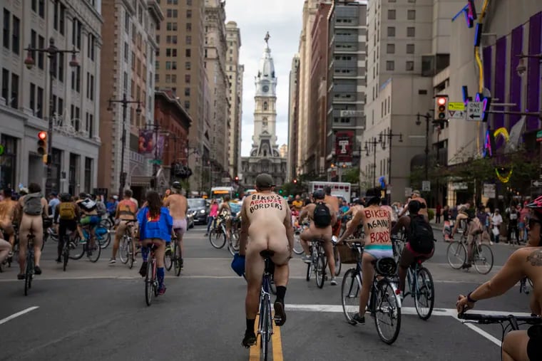 A man with the words "Bikers Against Borders,"painted on his back rides up South Broad Street during the Philadelphia Naked Bike Ride on Saturday, August 24, 2019.
