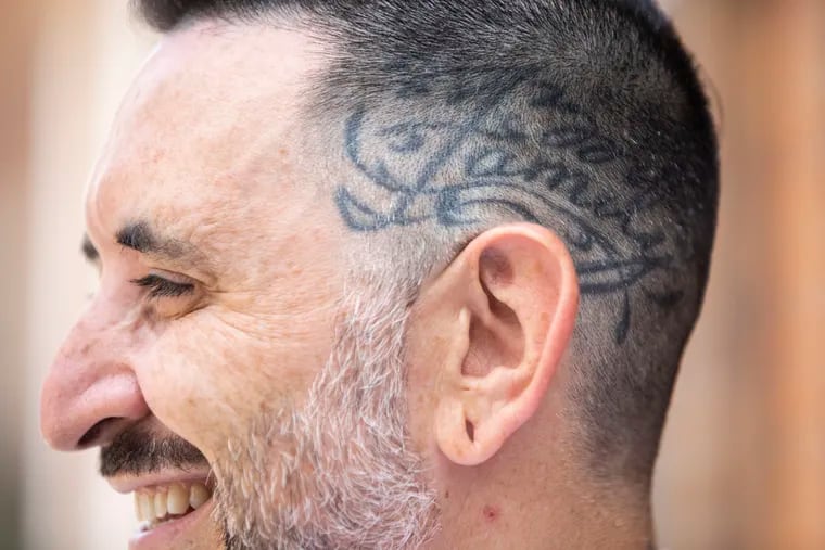 Andrew Miele shows his "Family" scalp tattoo outside his South Philadelphia home. The former tattoo artist wrote the children's book “What is a Vegan?” to help other parents teach their children what it means to be vegan.