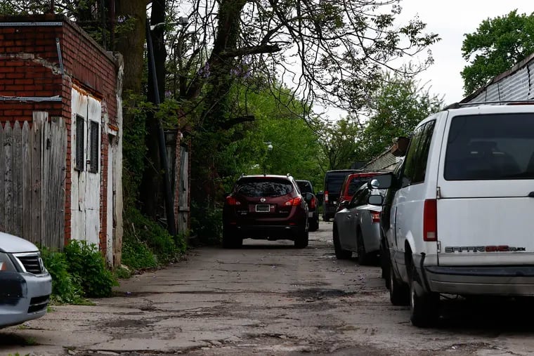Automobiles sit in the alleyway that is shared between houses on the 6000 block of Chester Avenue in Southwest Philadelphia and White's Auto on Thursday.  Three residents say the presence of the auto body shop has had disruptive and degrading effects on the neighborhood.