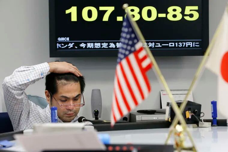 A money trader watches the monitor as a currency board updates the Japanese yen rate against U.S. dollar in Tokyo. The dollar has held up against most currencies, the euro and yen have fallen.