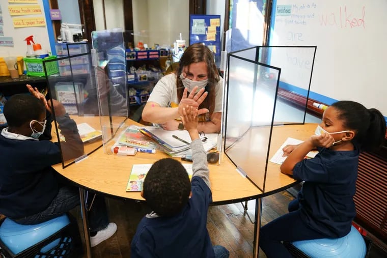 Teacher Michele Matza gives a high five to student Mershon Stevenson through a clear divider at Belmont Charter School in Philadelphia. Pennsylvania educators will soon be eligible for vaccination under a new plan announced by Gov. Tom Wolf.