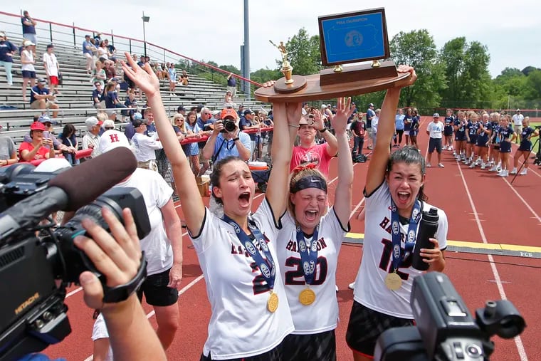 Harriton players (from left) Allison Schwab, Emily Stewart and Katelin Williams hold up the trophy after the Rams won the PIAA Class 3A lacrosse championship.