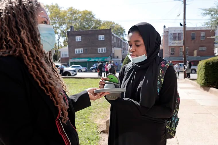 An Overbrook High administrator holds a device that allows a student to unlock her phone at the end of the school day. Overbrook is one Philadelphia School District school that uses magnetic pouches to halt student cell phone use during the day; the district is proposing to spend $5 million on pouches districtwide.