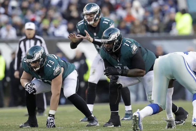 Eagles linemen Isaac Seumalo (left) and tackle Jason Peters prepare to block in front of Carson Wentz during a January game against the Cowboys.