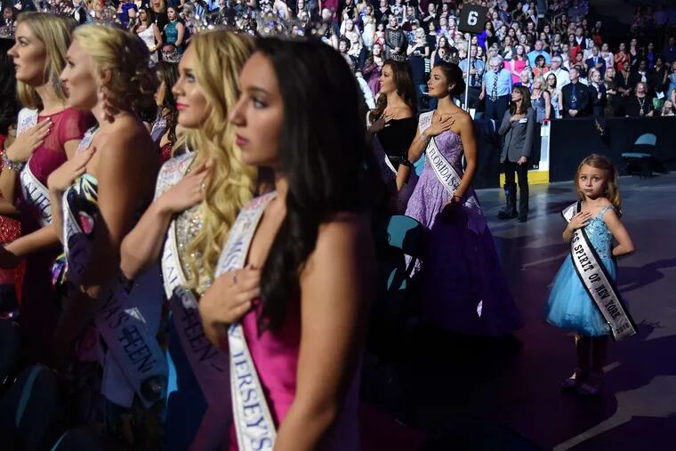 Aeowyn Holmes (right), 6, of Syracuse, N.Y., stands for the national anthem before the start of the pageant. Holmes is Mini Miss Spirit of New York. Augostina Mallous (center), 16, is the Miss America's Outstanding Teen from New Jersey.