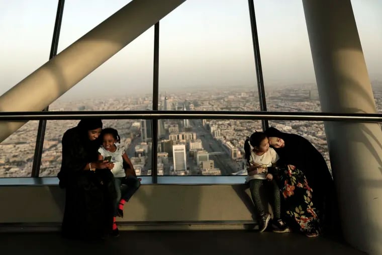 FILE - In this June 23, 2018 file photo, women hold their daughters as they visit the Four Seasons Skyline Tower, in Riyadh, Saudi Arabia. King Salman has extended monthly allowances for government employees, military personnel, pensioners, social security recipients and students into next year. The announcement, carried by the Saudi Press Agency on Tuesday, Dec. 18, 2018, comes on the same day the kingdom's 2019 budget is scheduled to be unveiled. (AP Photo/Nariman El-Mofty, File)