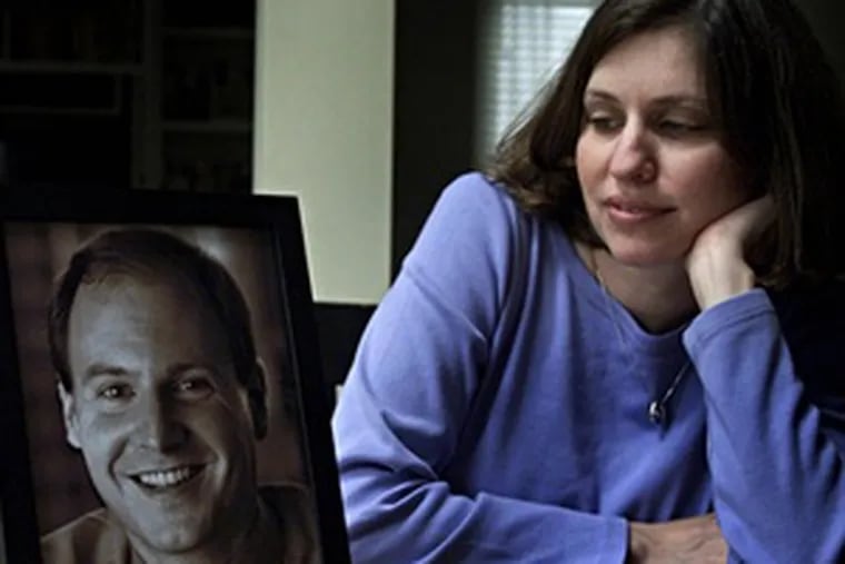 Susan Retik, a co-founder of the widows&#0039; support group Beyond the 11th, at home in Needham, Mass., with a portrait of her late husband, David. She will speak in Ambler tomorrow to raise funds for Afghan widows.