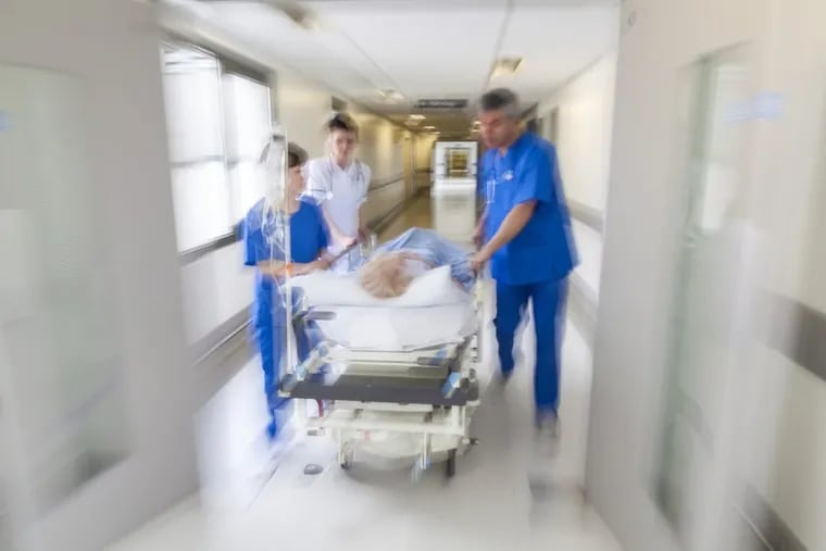 A motion-blurred photograph of a patient on stretcher or gurney being pushed at speed through a hospital corridor by doctors &amp; nurses to an emergency room. (istockphoto)