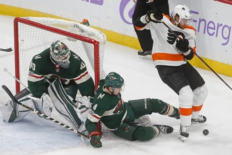 Minnesota Wild goalie Devan Dubnyk watches as Mike Reilly falls while defending Flyers’ Jake Voracek.