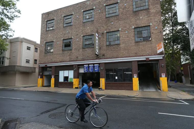 A cyclist passes a parking garage at 16th and Addison Streets. A developer plans to demolish the building for housing.