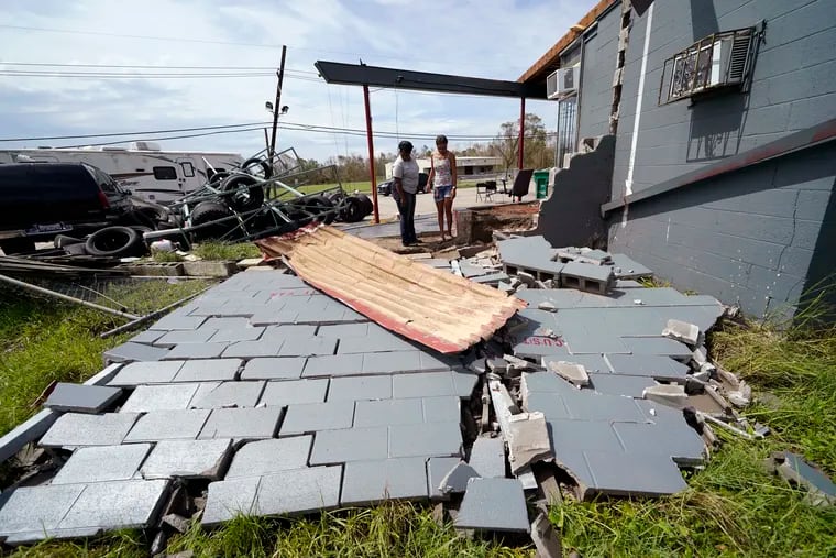 Monique Benjamin (left) and her daughter Amiah Winbush, 17, look at the damage to their car detailing business, in Lake Charles, La., in the aftermath of Hurricane Laura on Sunday. Two new storms have formed in the Atlantic Basin.