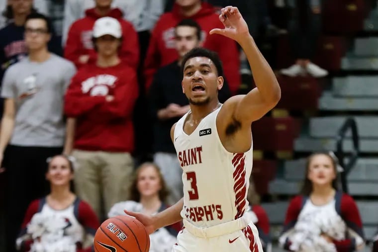 Saint Joseph's guard Jared Bynum signals while dribbling the basketball during a game.