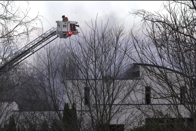 Firefighters work the scene of the suspected arson fire in a Colts Neck mansion where a family of four was found dead Tuesday.