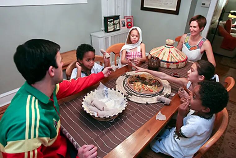 The Rupertus family in Mount Airy — (from left) dad Chris, Mihretu, Lucy, mom Kate, Annie, and Abel — share an Ethiopian meal to honor the adopted boys’ culture. (Steven M. Falk / Staff Photographer)