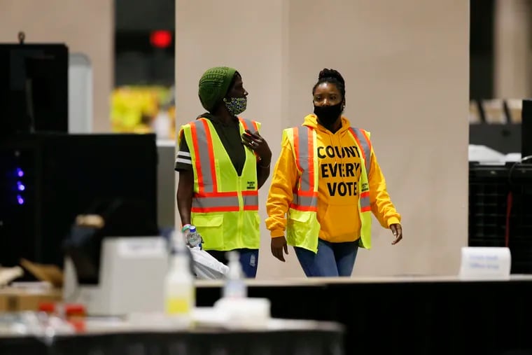 Two workers walk in the mailed in and absentee ballots room inside the Pennsylvania Convention Center in Philadelphia on Friday, Nov. 6.