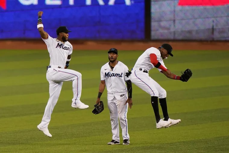 Miami's Monte Harrison, left, Starling Marte, center, and Lewis Brinson celebrate after beating the Phillies in the first game of Sunday's doubleheader.