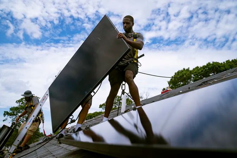 Employees of N.Y. State Solar, a residential and commercial photovoltaic systems company, install an array of solar panels on a roof in Massapequa, N.Y.