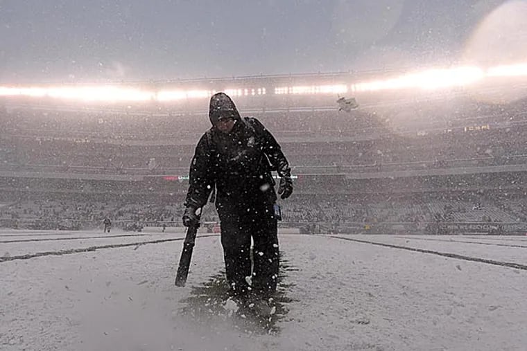 Eagles personnel clears snow from the field. (Michael Perez/AP)