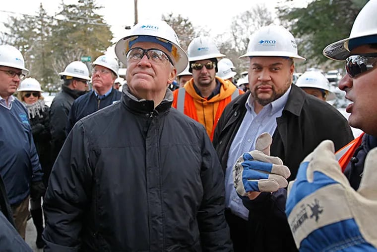 Pennsylvania Governor Tom Corbett, left, looks up at the PECO linement repairing the overhead power lines on Union Meeting Road in Blue Bell, PA and listens to Steven Singh, far right,  as he talks about the process of restoring power Southeastern Pennsylvania. The recovery continues after the ice storm left 500,000 without power. ( MICHAEL BRYANT / Staff Photographer )
