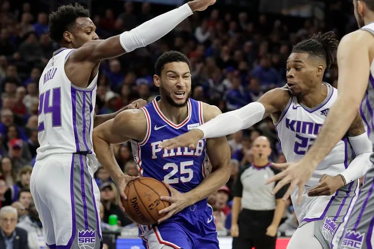 Sixers Ben Simmons drives to the net splitting King defenders Buddy Hield and Richaun Holmes in a game against the Sacramento Kings at the Wells Fargo Center in Philadelphia on November 27, 2019.