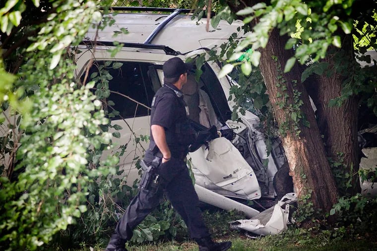 A police officer examines the mangled wreck of an SUV where a carjacked vehicle plowed into a crowd, killing three. (Alejandro Alvarez / Staff)