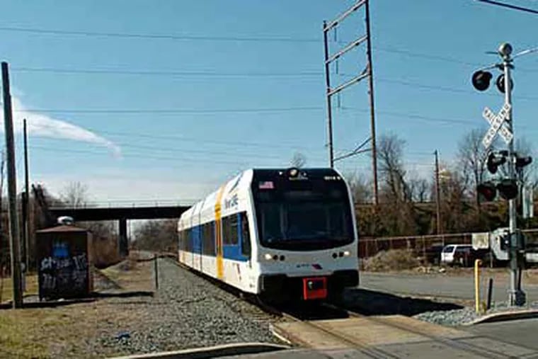 A River Line light rail-train bound for Trenton passes under the trestle in Pennsauken used by Amtrak&#0039;s Atlantic City Line, near the crossing at Derousse and Zimmerman Avenues.