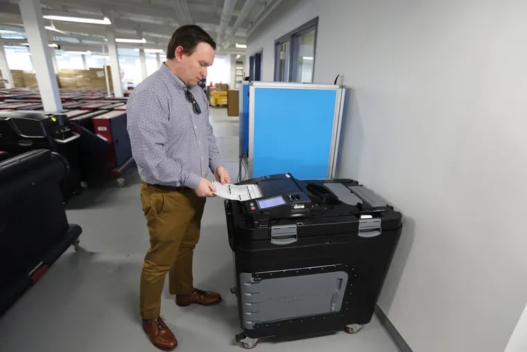 Mark Macekura from the Montgomery County election board feeds a paper ballet into a scanner.