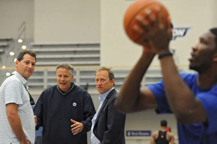 Sixers coach Brett Brown, managing owner Josh Harris (middle) and co-managing owner David Blitzer (left) watching Joel Embiid shoot baskets.