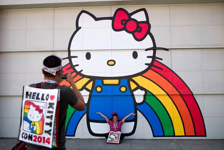 FILE - In this Oct. 30, 2014, file photo, Keith Nunez takes pictures of his wife, Carolina, at the first Hello Kitty fan convention, Hello Kitty Con, at the Geffen Contemporary at MOCA in Los Angeles. Hello Kitty might not have a mouth but she’s got a movie deal. Warner Bros.’ New Line Cinema announced Tuesday, March 5, 2019, that it has acquired film rights to Hello Kitty from the Japanese corporation Sanrio.