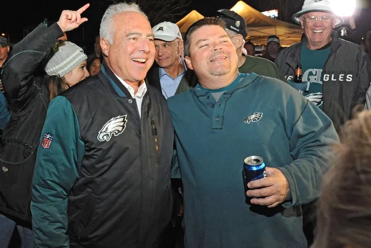Eagles owner Jeffrey Lurie (left), with fan Tom Baynes, has reason to smile. The team's value is up 900 percent since he bought it in 1994. NFL players' salaries have not risen at the same rate.