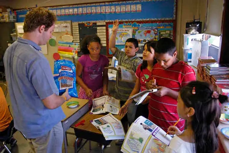 Teacher Theo Wood hands out food items so students can match them to their English wordsin their workbooks. The language class is part of their day in the district's summer program.
