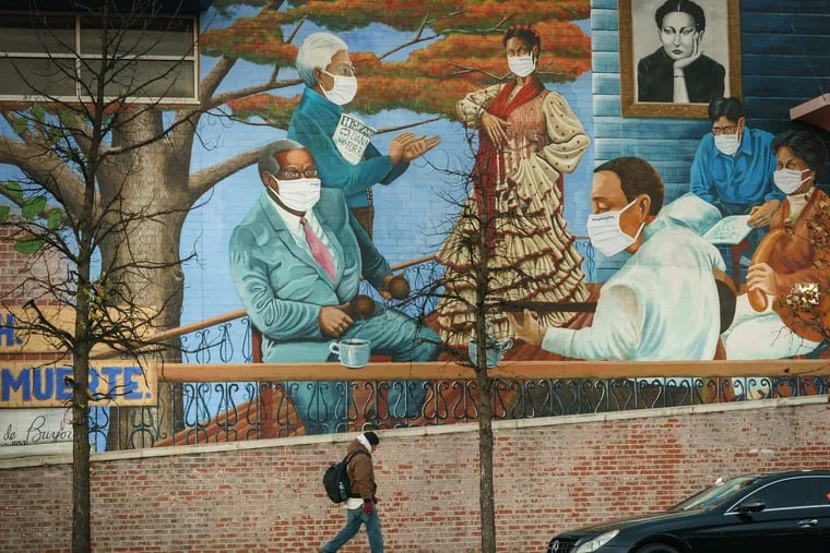 A pedestrian walks past a mural on the front wall of Julia de Burgos Elementary School, titled Latinx Heroes by artist Danny Torres in collaboration with Mural Arts Philadelphia.