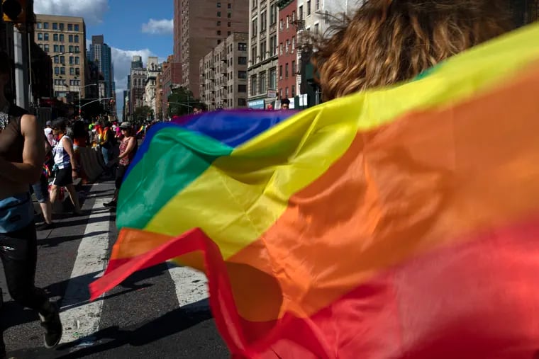 Parade-goers carrying rainbow flags walk down a street during the LBGTQ Pride march in New York, to celebrate five decades of LGBTQ pride, marking the 50th anniversary of the police raid that sparked the modern-day gay rights movement. Legislation that would create new protections for LGBTQ Americans is stalling out in the U.S. Senate.