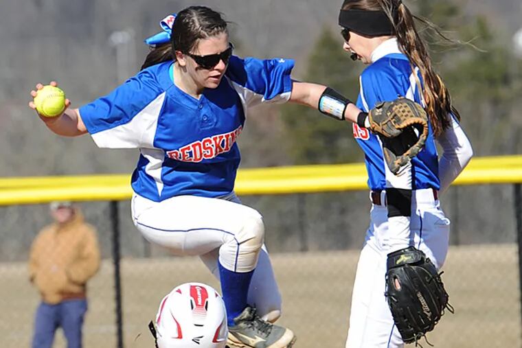Neshaminy's Sophie Beretski, left, valuts over a sliding Souderton runner Missy Wile, right, after making the force out at second base in the secon inning April 1, 2015 in Souderton, Pa. Looking on at right is Neshaminy' ssecond baseman Hunter Hart. (Bradley C Bower/Staff Photographer)