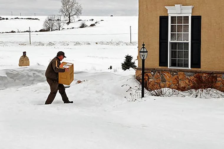 UPS driver Bruce McAllister treks through an unshoveled sidewalk as he makes a delivery in a residential area in Oxford last month. (Tom Gralish / Staff Photographer)