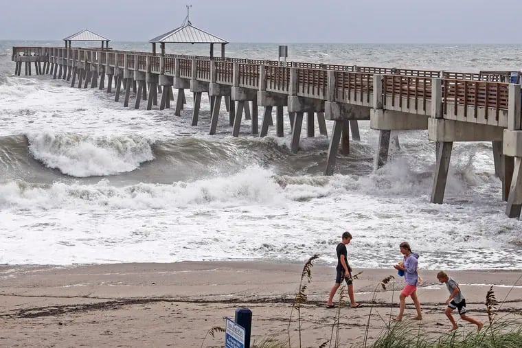 Beach goers get a closer look of the waves crashing against the Juna Beach Pier in Juno Beach, Fla., Monday, Sept. 2, 2019, as Hurricane Dorian crawls toward Florida, while the storm continues to ravage the Bahamas. (Carl Juste/Miami Herald via AP)