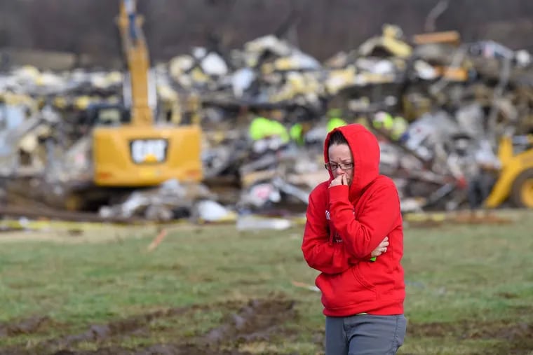 A woman walks away from what is left of the Mayfield Consumer Products Candle Factory as emergency workers comb the rubble after it was destroyed by a tornado in Mayfield, Kentucky, on Saturday, Dec. 11, 2021. (John Amis/AFP/Getty Images/TNS)