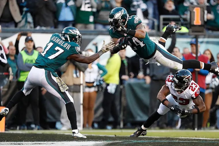 Ryan Mathews dives over the Falcons’ Robert Alford, as the Nelson Agholor reaches out to his teammate.