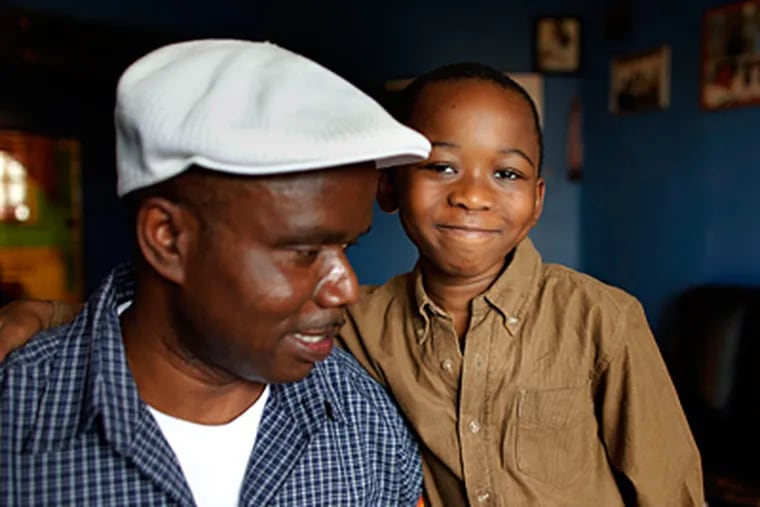 Menduawor Comgbaye, 6, and his father, Gbahtuo, at their S.W. Phila. home. Comgbaye, a W. African immigrant, pleaded for school officials' help. After being treated at Children's Hospital, the boy hasn't been back to school. (Laurence Kesterson / Staff Photographer)