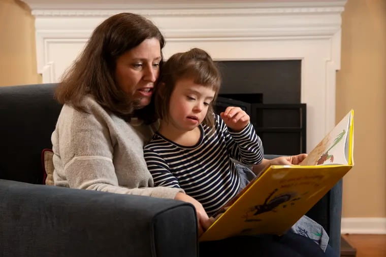 Maggie Gaines and her husband are pressing the Tredyffrin/Easttown School District to change its threat assessment policies after they say school officials reported their 6-year-old daughter, Margot, to police. Margot, who has Down syndrome, pointed her finger at a teacher and said "I shoot you," according to her mother. They are shown at home reading a book on Feb. 7, 2020.