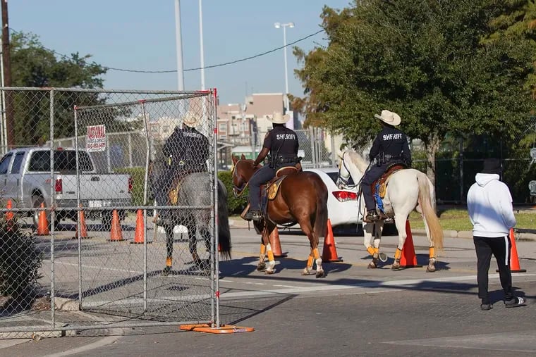 Members of the Harris County Mounted Police Unit pass through the gates of Astroworld at NRG on Saturday. Several people died and numerous others were injured in what officials described as a surge of the crowd at the music festival while Travis Scott was performing Friday night.