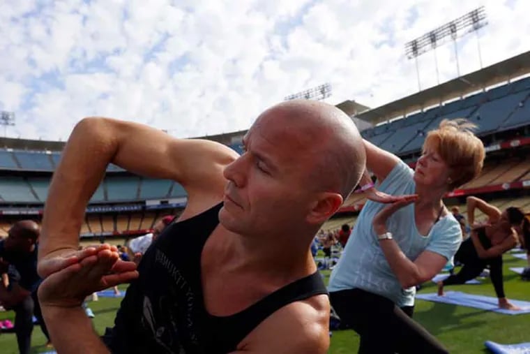 Brian Farrell, left, participates in a yoga class lead by Mia Togo from Yogaworks after the Dodgers game on May 17, 2015 at Dodger Stadium, in Los Angeles. The yoga class was 30 minutes long, and the field was filled with participants.