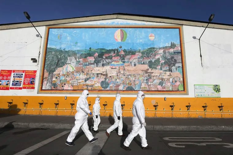 Workers in protective body suits walk past sinks for hand washing at the "Corabastos," one of Latin America's largest food distribution centers, as they work to disinfect it to help contain the spread of the new coronavirus in Bogota, Colombia, on Friday.