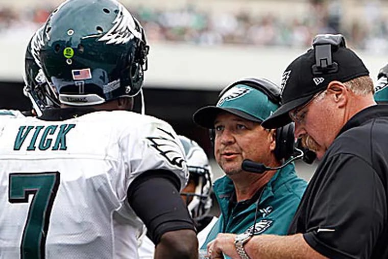 Andy Reid and Marty Mornhinweg discuss strategy with Michael Vick during Sunday's win. (David Maialetti/Staff Photographer)