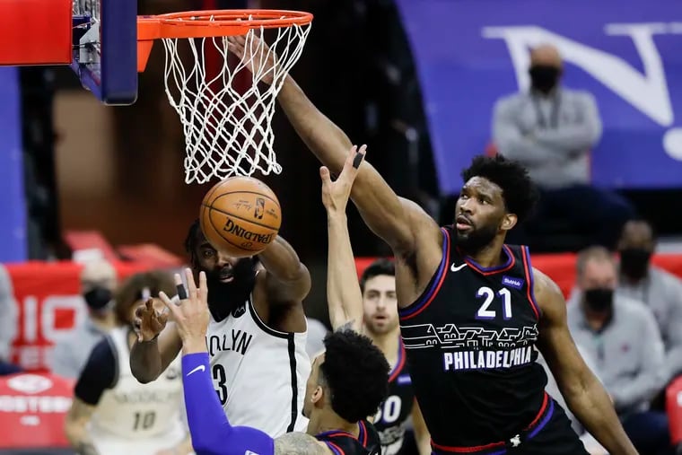 Brooklyn Nets guard James Harden passes the basketball while defended by Sixers center Joel Embiid (21) and forward Danny Green on Feb. 6.