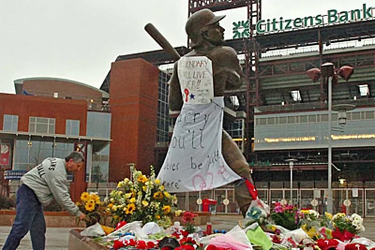 Joe Rubino, 49, places flowers at the impromptu memorial to Harry Kalas growing at the statue of Mike Schmidt at Citizens Bank Park, the day after Kalas died. ( Clem Murray / Staff Photographer )